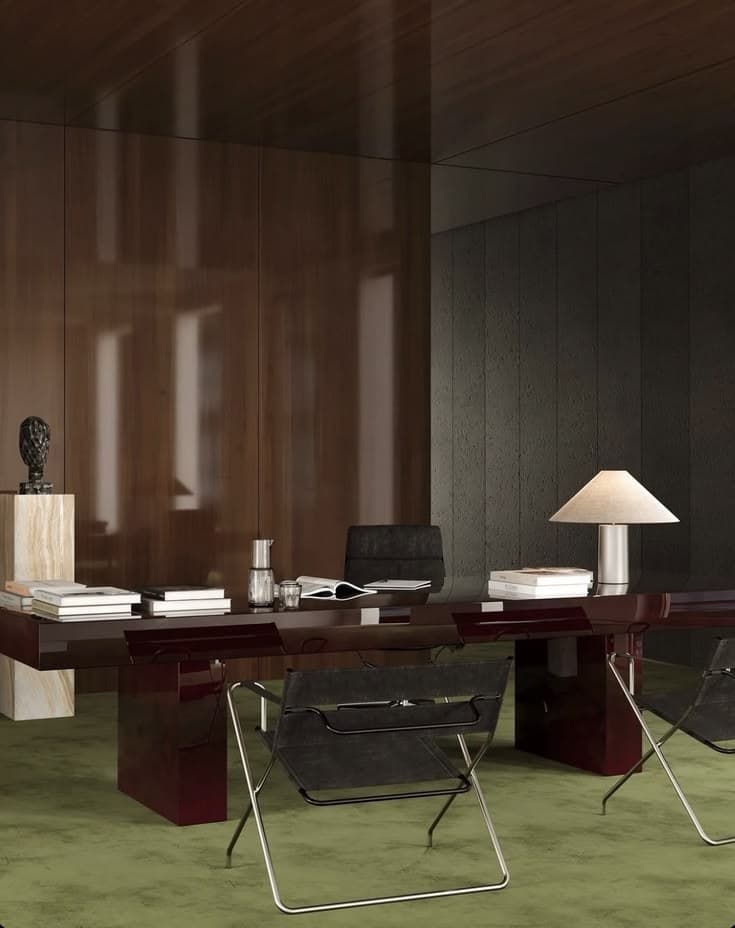 Lacquered desk with books, a cone lamp and folding leather chairs on a green carpet