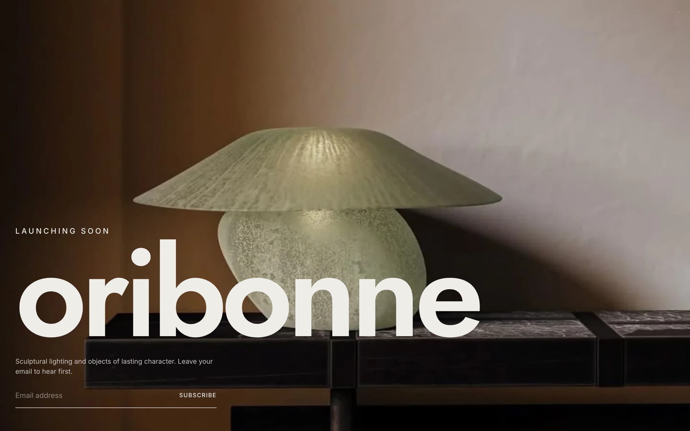 Oribonne launch page: a sculptural green glass lamp on a dark stone table under the oversized oribonne wordmark